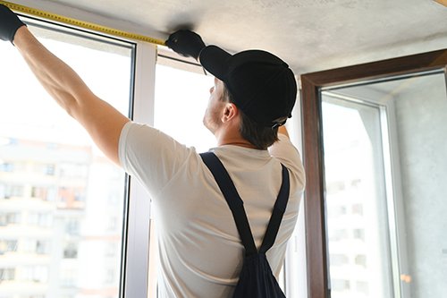 A technician measuring a window opening at a home install.